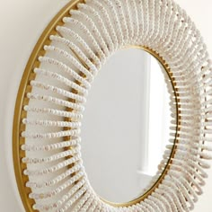 a white and gold circular mirror hanging on the wall