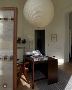 a room with a desk, chair and hanging light fixture in the middle of it