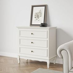 a white chest of drawers sitting next to a chair