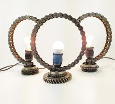 two light bulbs sitting on top of a metal object with gears in the shape of heart