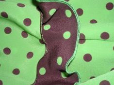 a green and purple polka dot fabric with white dots on the bottom half of it