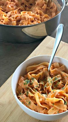 two pans filled with pasta on top of a wooden cutting board