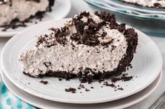 a slice of oreo cake on a plate with the rest of the pie in the background