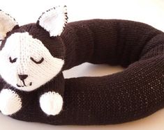 a black and white knitted animal head rester on a white table with it's eyes closed