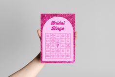 a person holding up a pink bridal bingo game