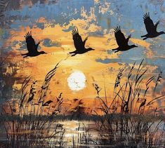 three birds flying in the sky over water at sunset with grass and reeds on either side