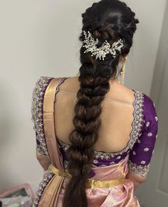 a woman with long hair wearing a purple and gold sari, braided into a fishtail hairstyle