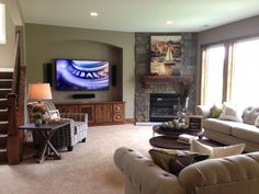 a living room filled with furniture and a flat screen tv mounted on the wall above a fire place