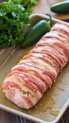 sliced ham on a baking sheet with green peppers and cucumbers in the background