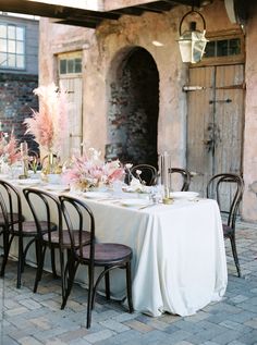 the table is set with white linens and pink flowers