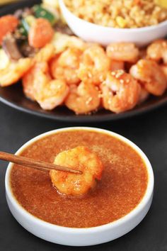 a bowl of soup with chopsticks in front of it and shrimp on the side