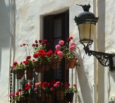 a balcony with flowers and a lamp on the side of it that is attached to a building