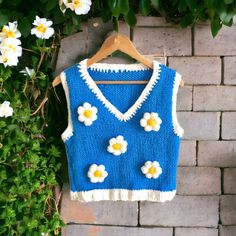 Elevate your wardrobe with our Knit Sweater Vest, a perfect blend of boho chic and cozy comfort. This handmade crop vest features charming daisy appliques, adding a touch of whimsy to any outfit. With its chunky knit texture and stylish V-neck design, this vest is a versatile piece that can be dressed up or down. Ideal as a unique gift, this flower-adorned vest is sure to become a favorite in your collection. Design: Chunky knit with daisy appliques Fit: Crop vest style for a trendy look Materia Yarn Daisy, Flower Vest, Daisy Applique, Vest Handmade, Knit Slouchy Hats, Festival Mode, Crop Vest, Knit Sweater Vest, Patchwork Jacket