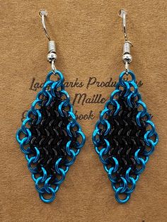 a pair of blue and black earrings on top of a piece of paper