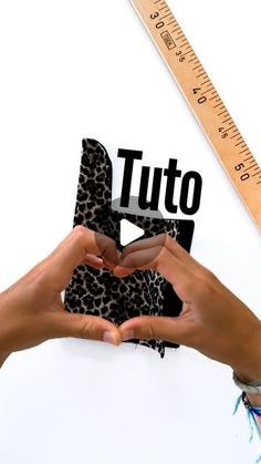 two hands holding up a pair of shoes with the word tuto on it and a ruler next to them