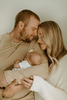 a man and woman holding a baby in their arms