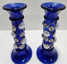 two blue glass candlesticks sitting next to each other on a white table top