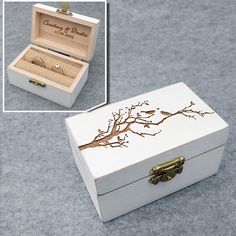 a white box with a tree design on the lid and an open ring box in it