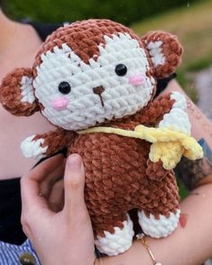 a person holding a small stuffed animal in their hands with the monkey on it's back