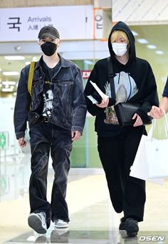 two people wearing face masks while walking through an airport