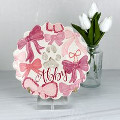 a pink and white plate with bows on it sitting next to a vase filled with tulips