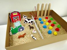 an open cardboard box filled with farm animals and wooden pegs on top of it