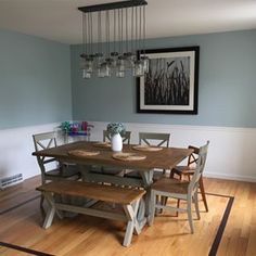 a dining room table with chairs and a bench next to the wall in front of it