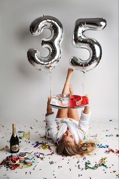 a woman laying on the ground with balloons and confetti in front of her