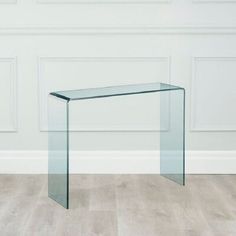 a glass table sitting on top of a hard wood floor next to a white wall