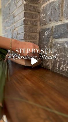 a woman's hand on the edge of a wooden table next to a brick wall