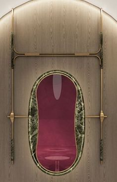 an oval mirror with a red chair in the middle and gold trim around it's edges