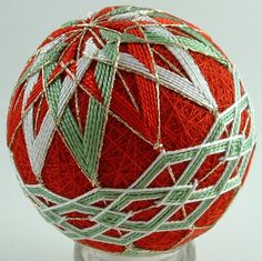 a red ball with green and white lines on it's side, sitting on a glass base