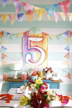 the table is set for a five year old birthday party with colorful decorations and bunting