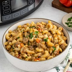 a white bowl filled with pasta and meat next to an instant pot roaster oven