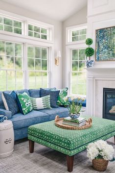 a living room with blue couches and green pillows on the coffee table in front of a fireplace