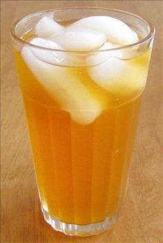 a glass filled with ice sitting on top of a wooden table