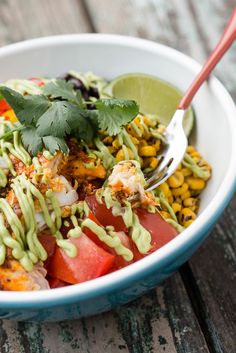 a white bowl filled with salad and topped with cilantro, avocado