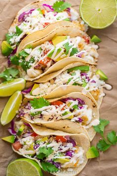 fish tacos with cole slaw, limes and cilantro on parchment paper