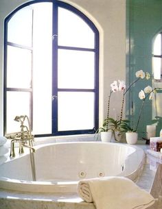 a large white bath tub sitting in a bathroom next to a window with flowers on it