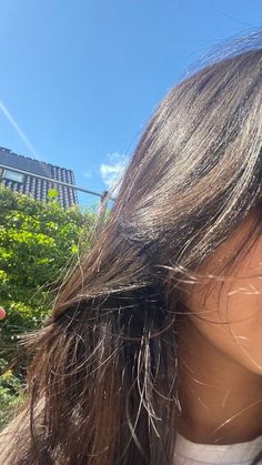 a woman holding a cell phone up to her ear and taking a selfie in front of a building