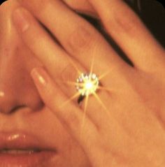 a woman holding her hand to her face with a diamond ring on it's finger