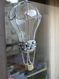 a glass lantern with beads and chains hanging from it's side