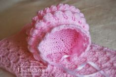 a pink crocheted hat and booties on a bed