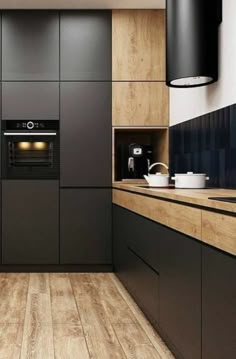 a modern kitchen with wood floors and black cabinets on the wall, along with an oven