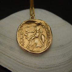 a gold necklace with an ancient coin on it