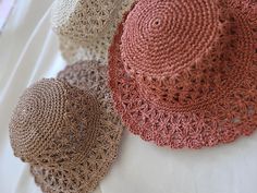 three crocheted hats sitting on top of a white table next to each other