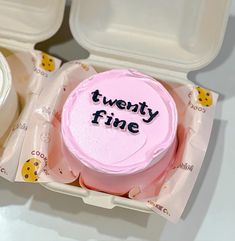 a pink frosted cake with the words twenty fine written on it in a plastic container