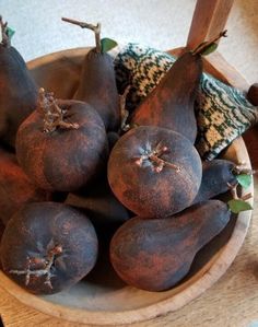 a wooden bowl filled with ripe fruit on top of a table