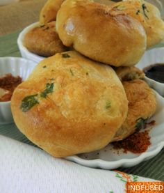 some bread rolls are stacked on top of each other in small bowls with dipping sauces