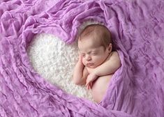 a baby is laying in a heart shaped blanket